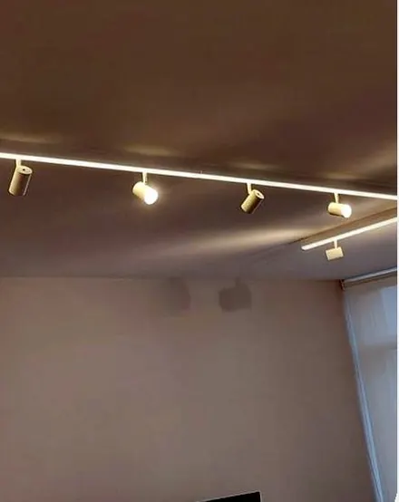 Trilho com spots direcionados e perfil de LED em ambiente comercial