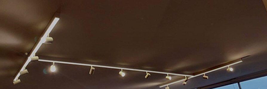 Trilho de iluminação com spots distribuídos ao longo do teto de sala ampla, executado pela MTECH Elétrica